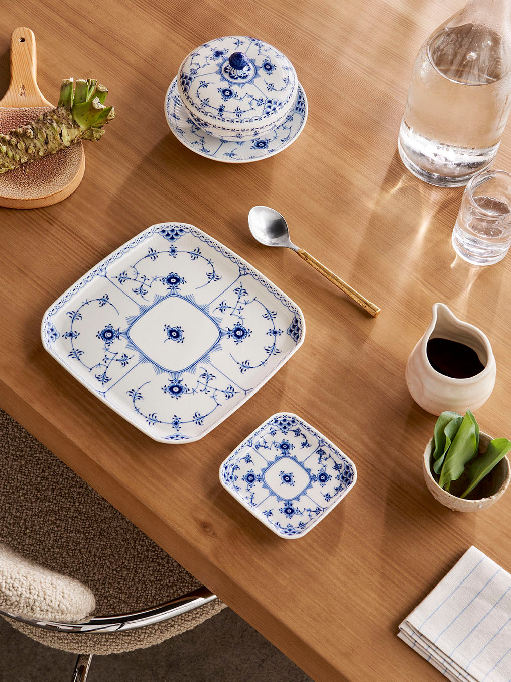 Dining table with blue Fluted Half Lace dishes, a spoon, and a glass of water.
