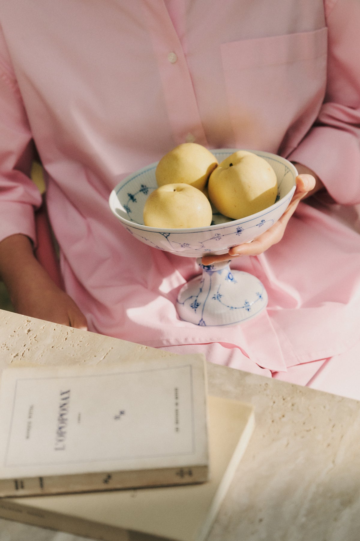 Person holding a Blue Fluted Plain bowl on foot with yellow apples.