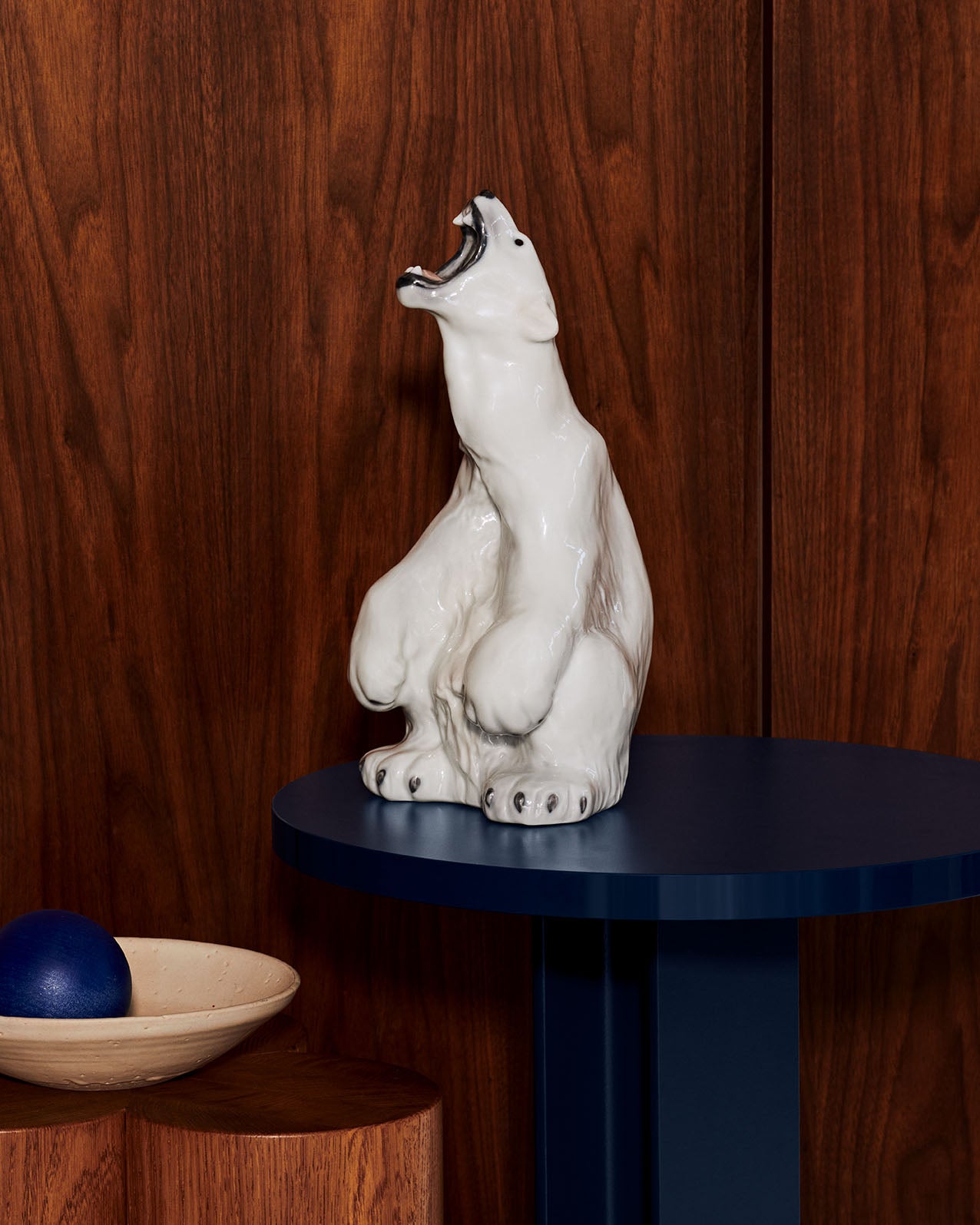 White porcelain roaring Polar Bear on a dark blue table against a wooden background