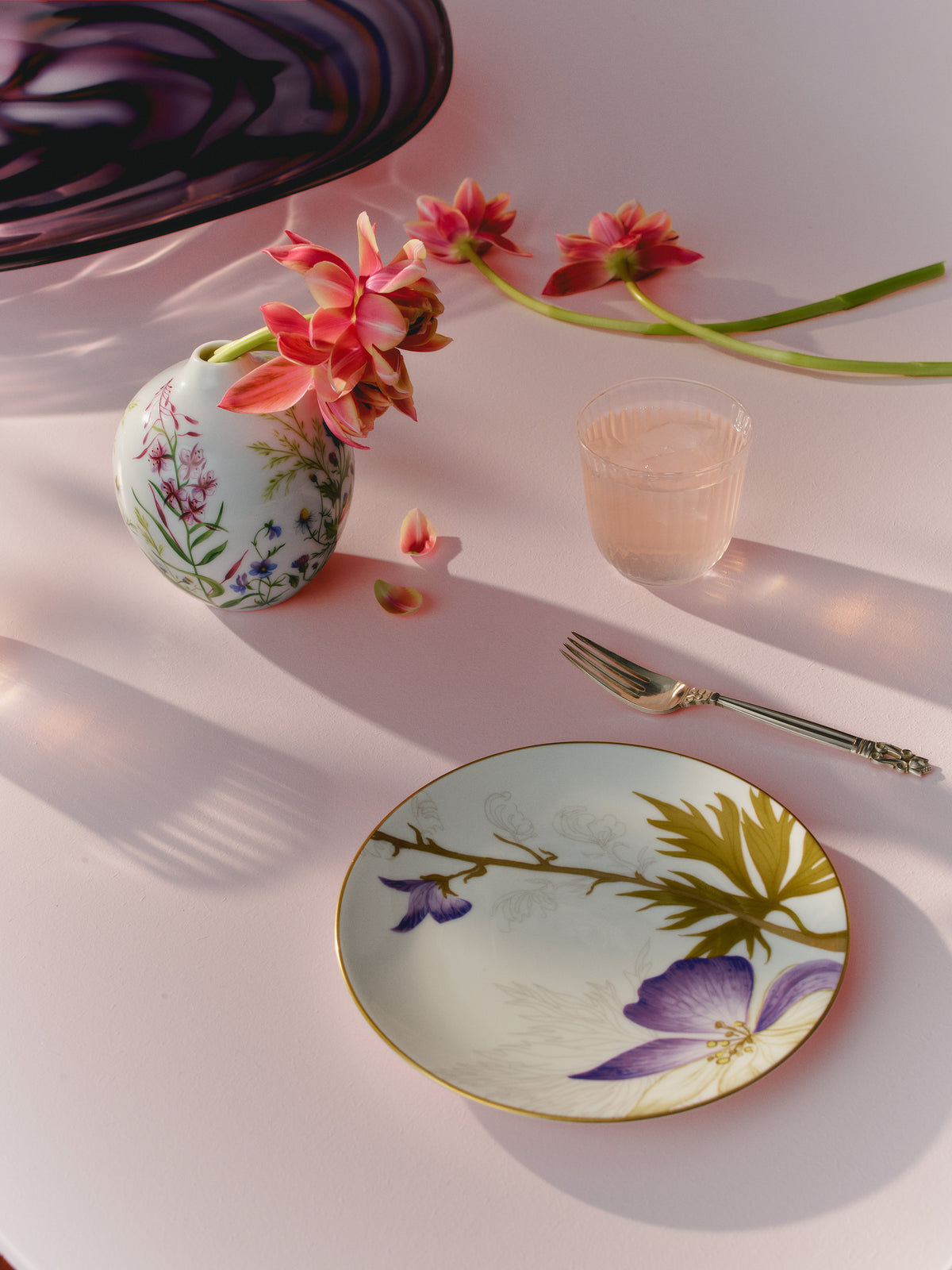 Decorative Flora plate on a light pink surface with a Spring vase with flowers