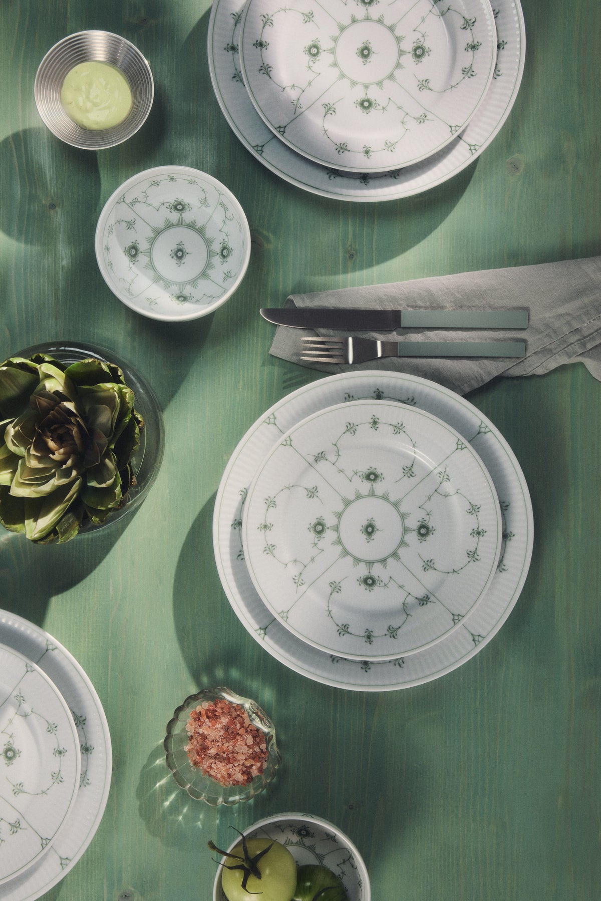 A Decorative table set with Green Fluted Plain plates and bowls on a green table.