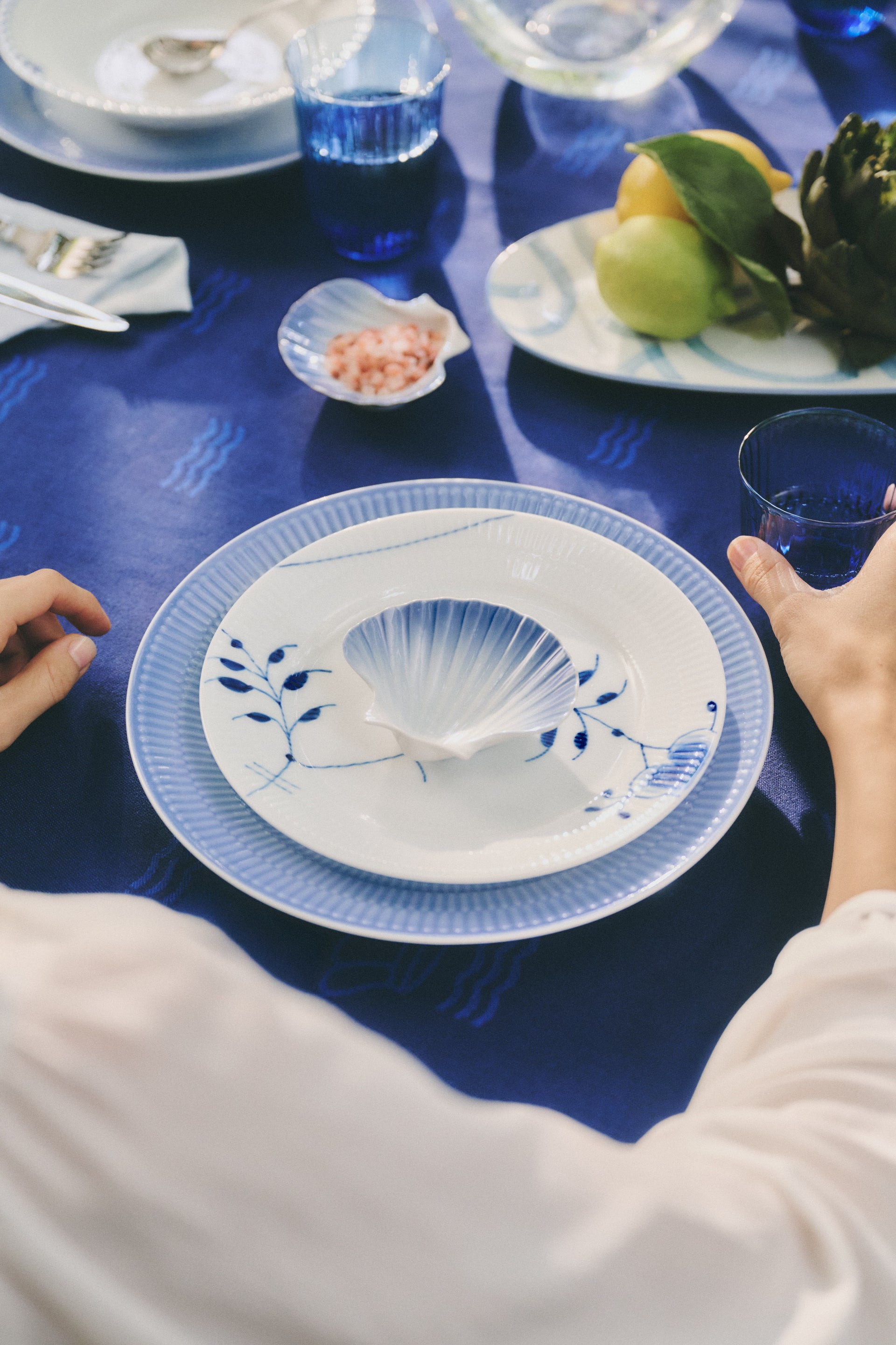 Blue Waves tablecloth with a decorative blue Iris plate featuring the blue shell dish, surrounded by other plates and Fluted glasses.