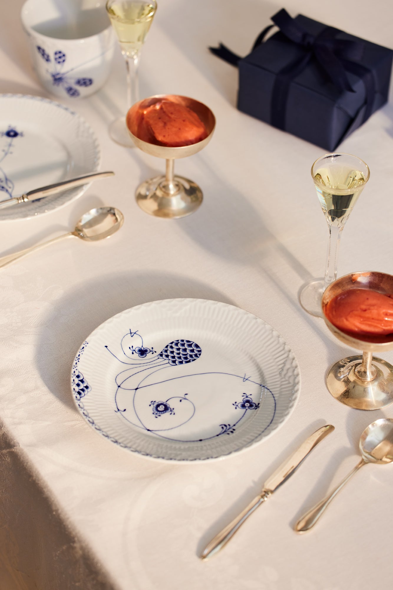 Dining table setting with Royal Creatures plates, glasses, and cutlery on a white tablecloth.